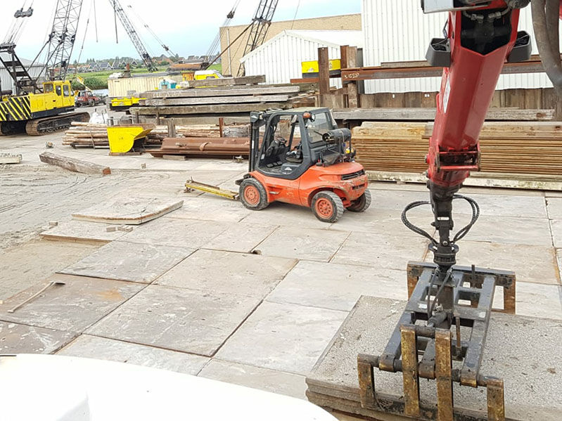 Betonplaten in gebruik bij een industriehaven, bieden een duurzame en belastbare ondergrond voor zware voertuigen en vracht