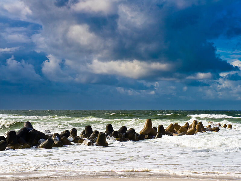 Grote betonnen tetrapods in een havengebied die functioneren als golfbrekers, ter bescherming van de kust tegen erosie door golven